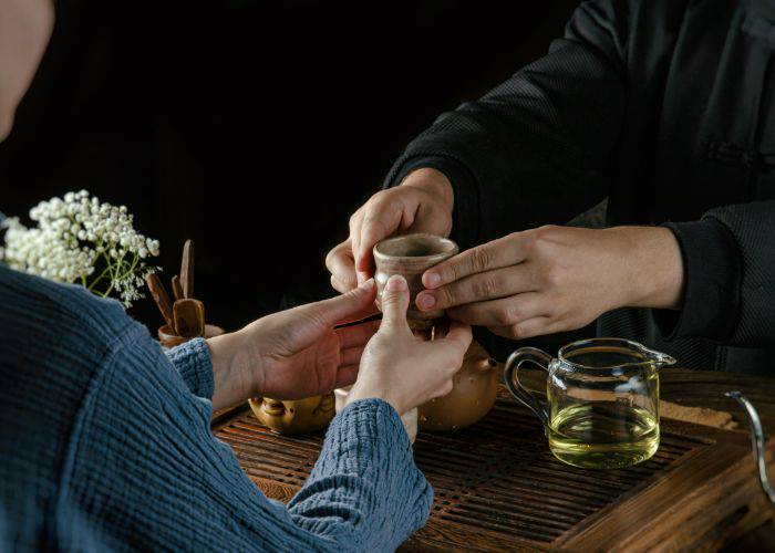 A person being served Japanese tea in an atmospheric, traditional setting.